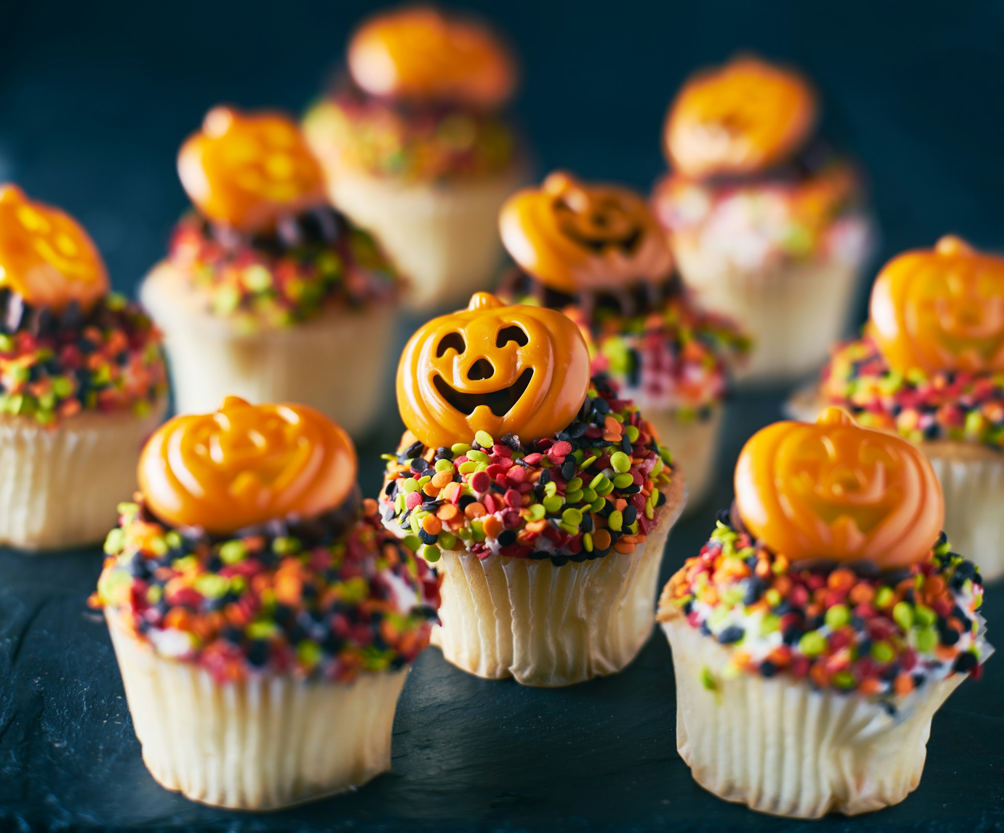 festive halloween pumpkin cupcakes with chocolate frosting and colorful sprinkles